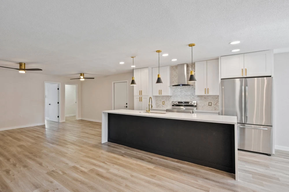 A clean kitchen with white cabinets and wood floors.