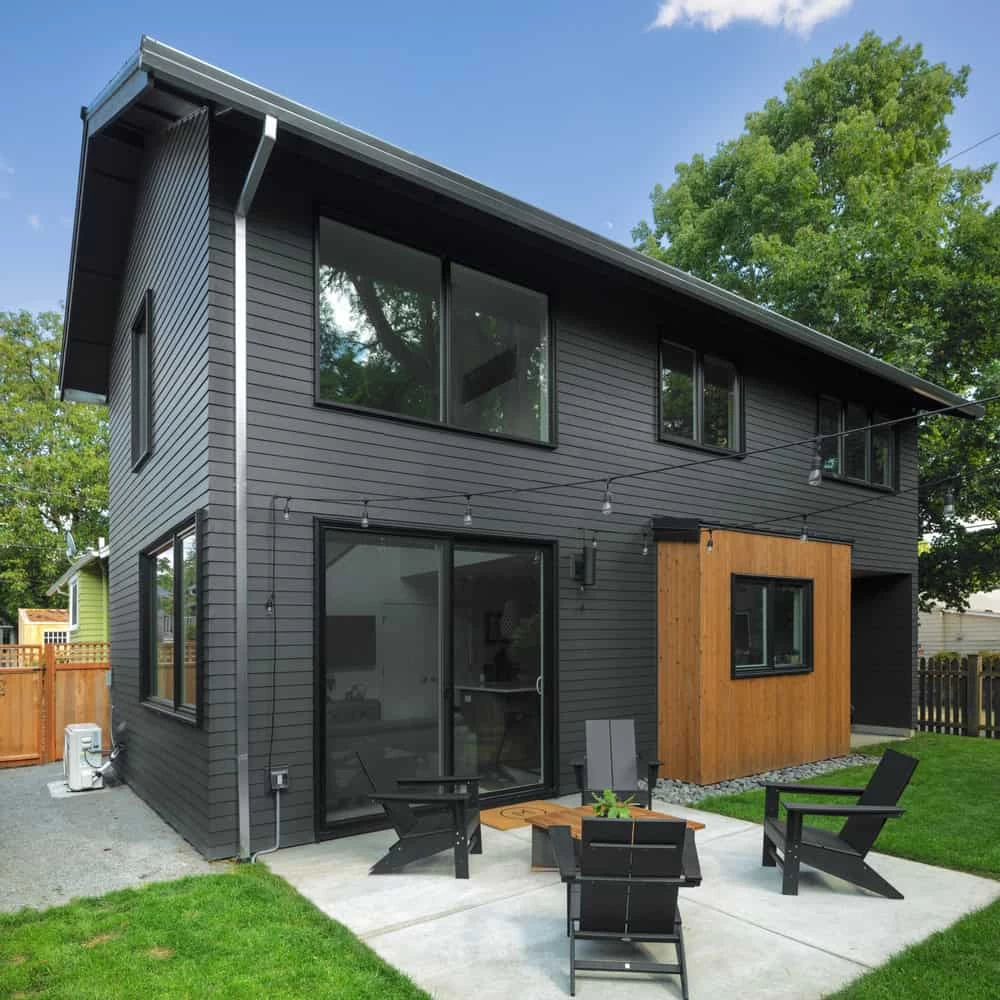 A modern home with black siding and wooden decking.
