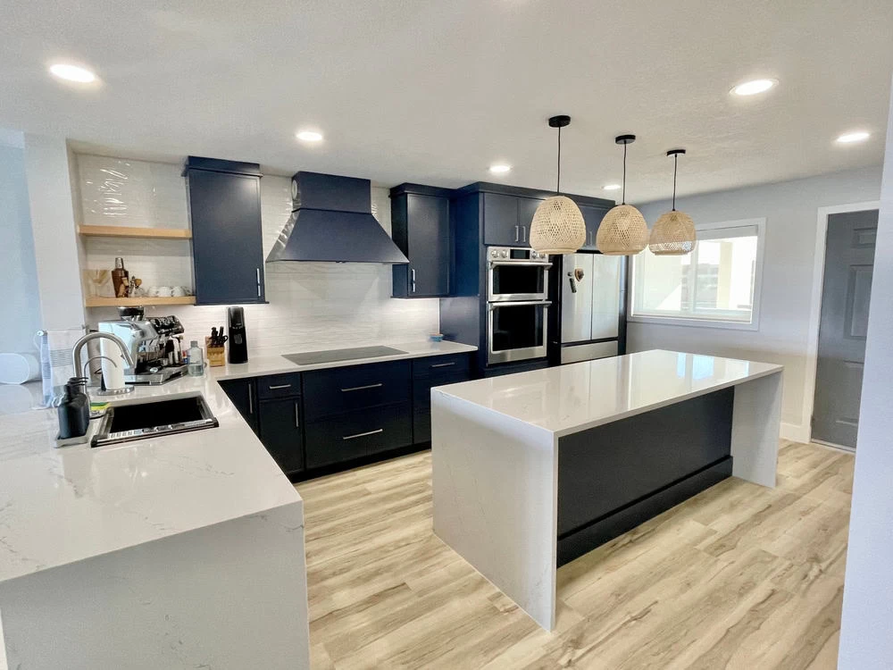 A kitchen with blue cabinets and white counter tops.