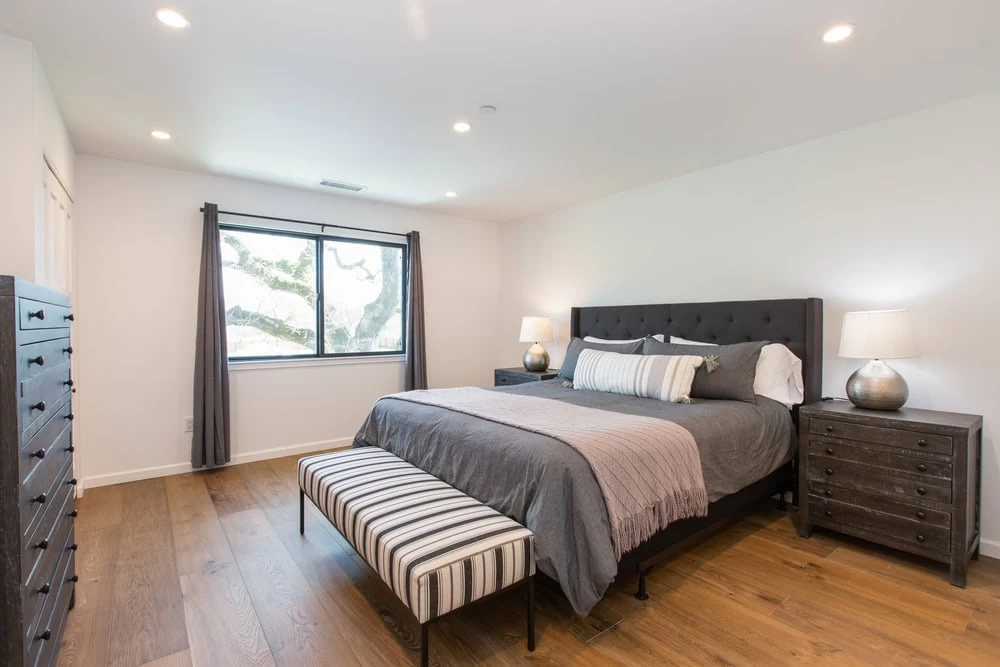 A bedroom with a bed, dresser and nightstands.